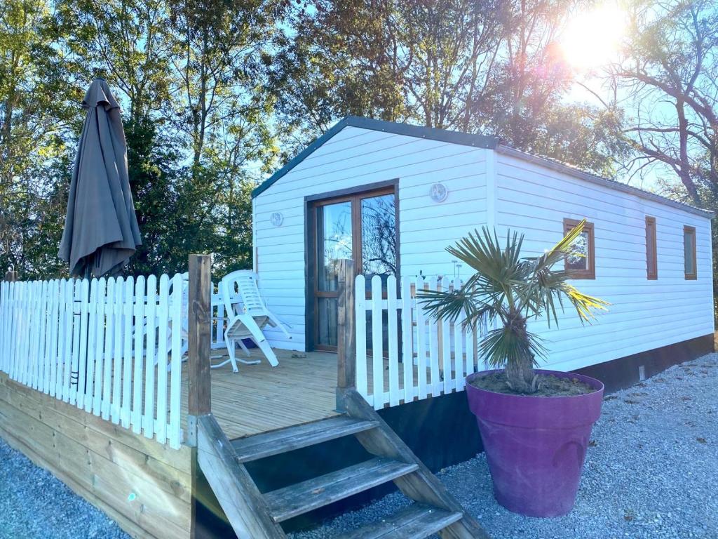 a white tiny house with a porch and a potted plant at La Maison Blanche in Courlans