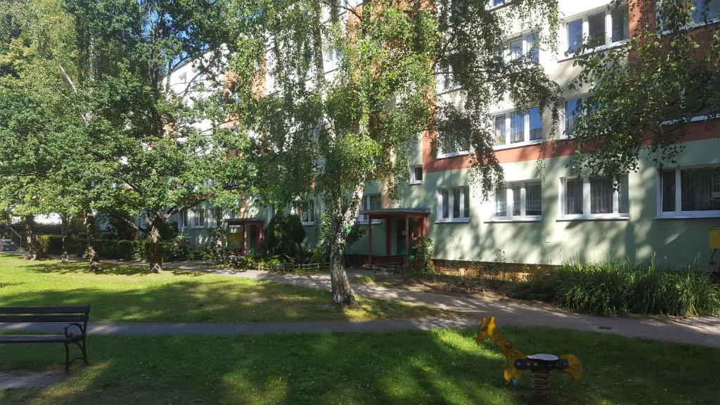 a park in front of a building with a bench at Stara Piekarnia - Apartament Dworcowa in Olsztyn