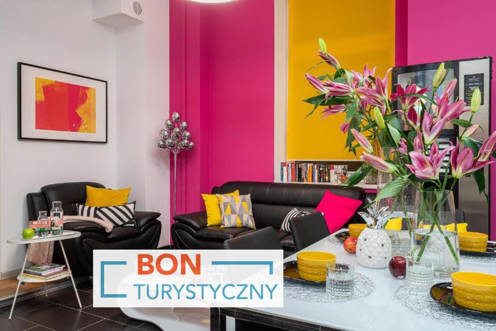 a living room with pink and yellow walls and a table with flowers at Absynt Hostel Wrocław in Wrocław