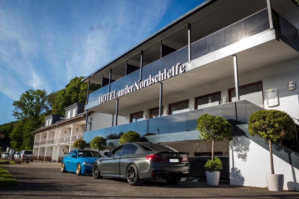 zwei vor einem Gebäude geparkt in der Unterkunft Hotel an der Nordschleife in Adenau