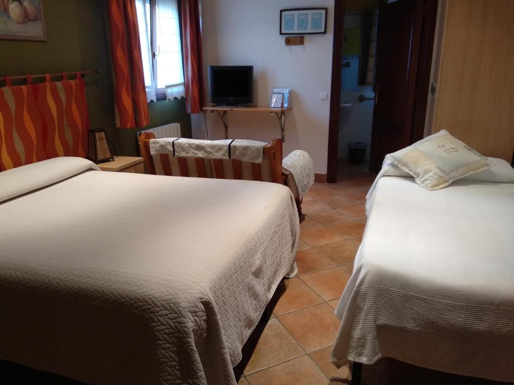 a hotel room with two beds and a television at Pension zelaigane in Mendexa