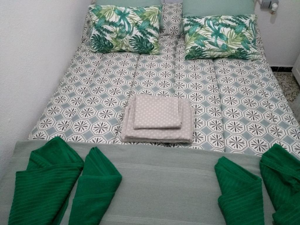 a bed with green pillows on top of it at Alojamiento con encanto in Vejer de la Frontera