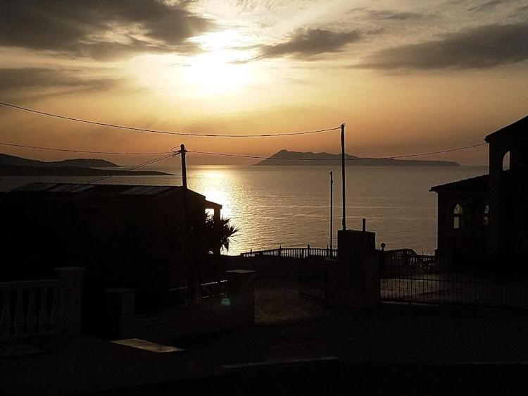 una puesta de sol sobre un cuerpo de agua con la puesta de sol en spiros maria studios en Corfú