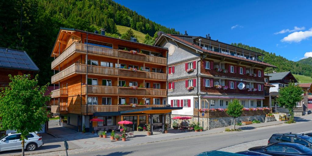 eine Gruppe von Gebäuden auf einer Straße mit einem Berg in der Unterkunft Kienle - das Kräuterhotel in Balderschwang