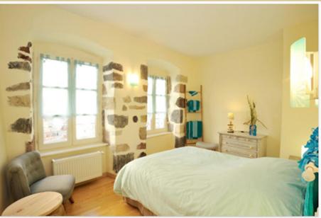 1 dormitorio con 1 cama, 1 silla y ventanas en Relais du Noble Voyageur en Brioude