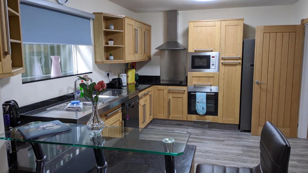 una cocina con una mesa con un jarrón de flores. en Glennydd House en Llangefni