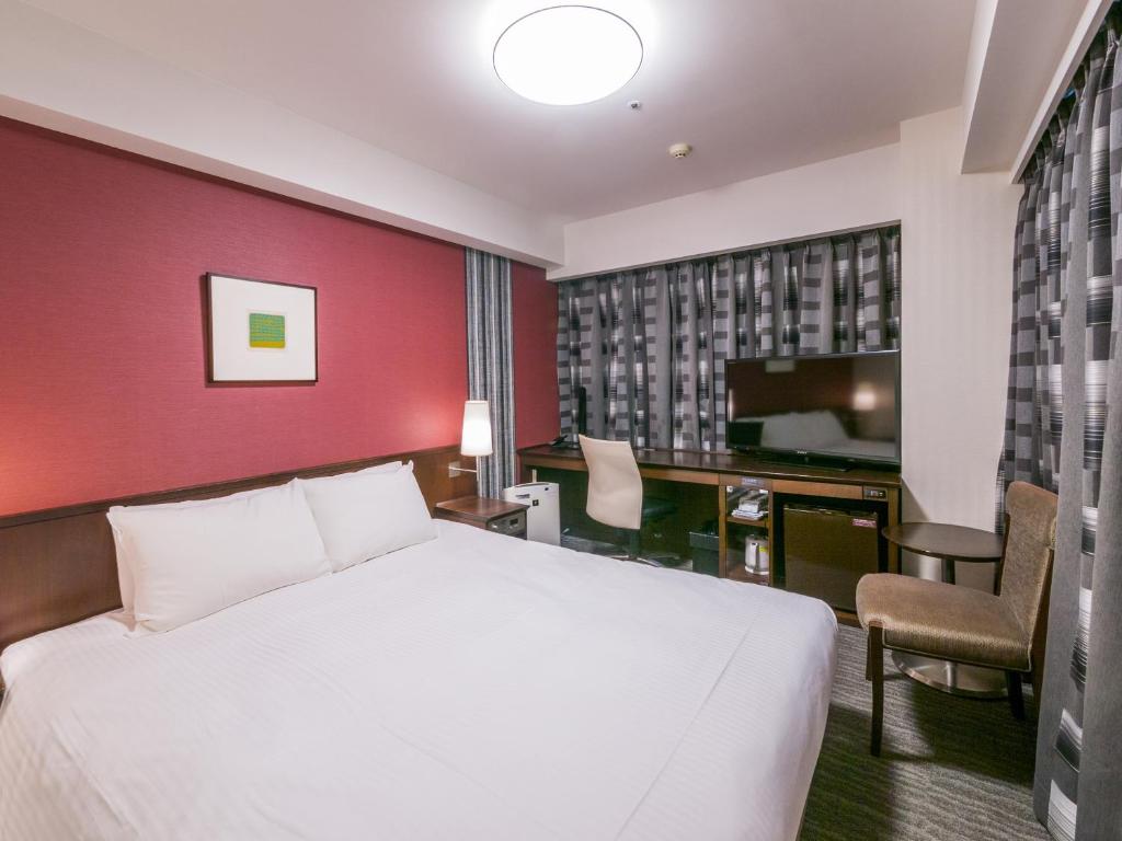 a hotel room with a white bed and a tv at Richmond Hotel Fukuoka Tenjin in Fukuoka