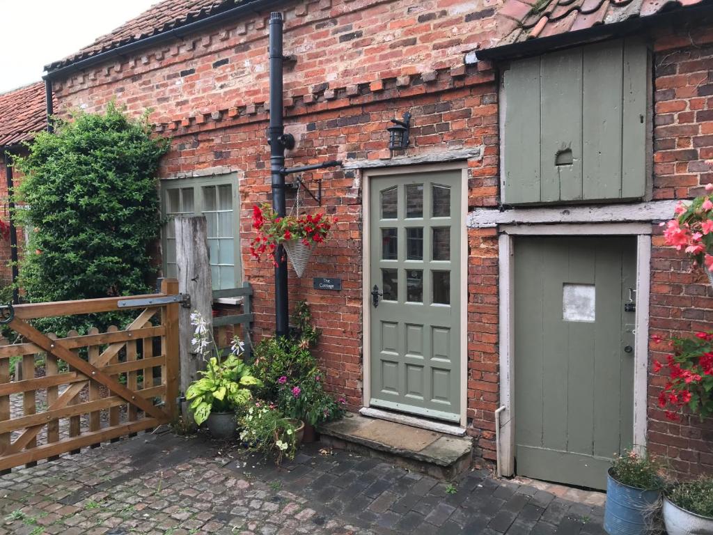 une maison en briques avec deux portes et une clôture dans l'établissement Bottesford Cottage - Leicestershire, à Bottesford