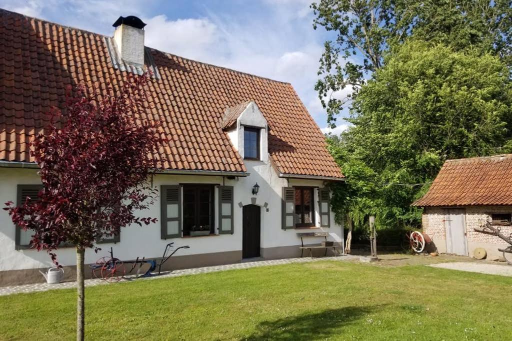 Casa blanca con techo rojo y patio en Cozy studio on a quaint farm, en Kruibeke