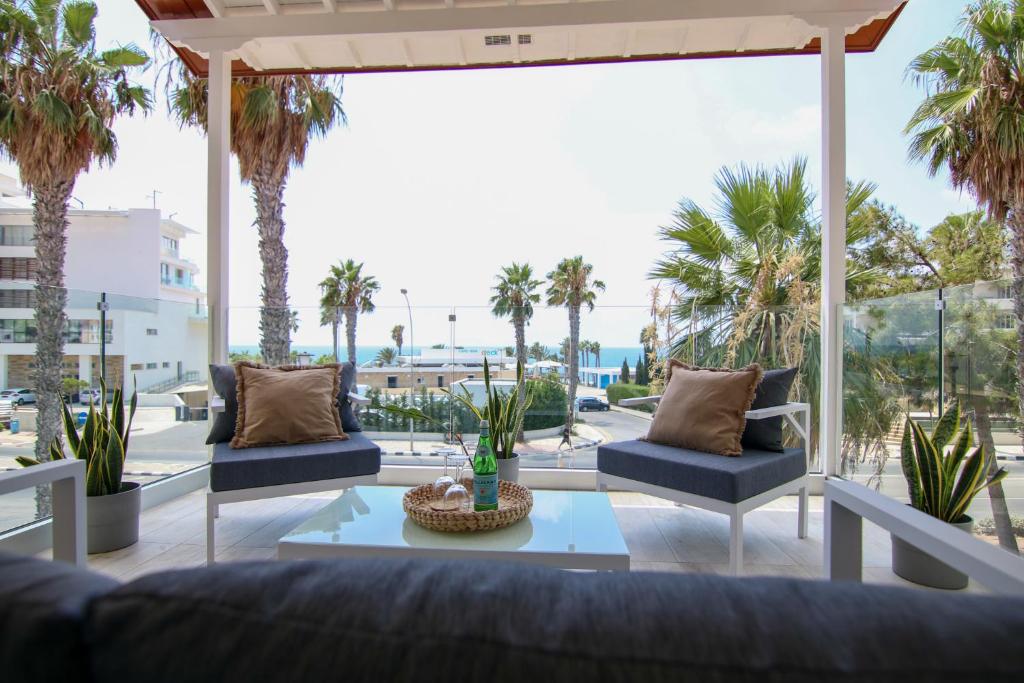 a patio with chairs and a table and palm trees at Phaedrus Living: Seaside Luxury Flat Limnaria 152 in Paphos