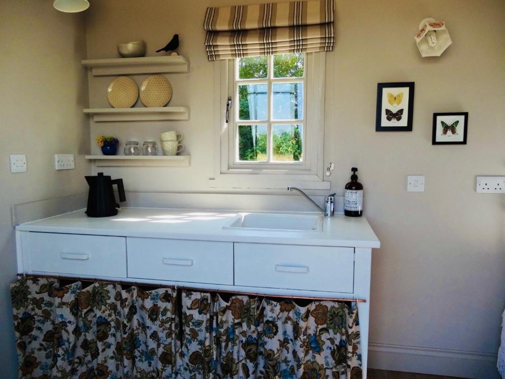 una cucina con lavandino bianco e finestra di The Oaks Glamping - Rubie's Shepherds Hut a Colkirk