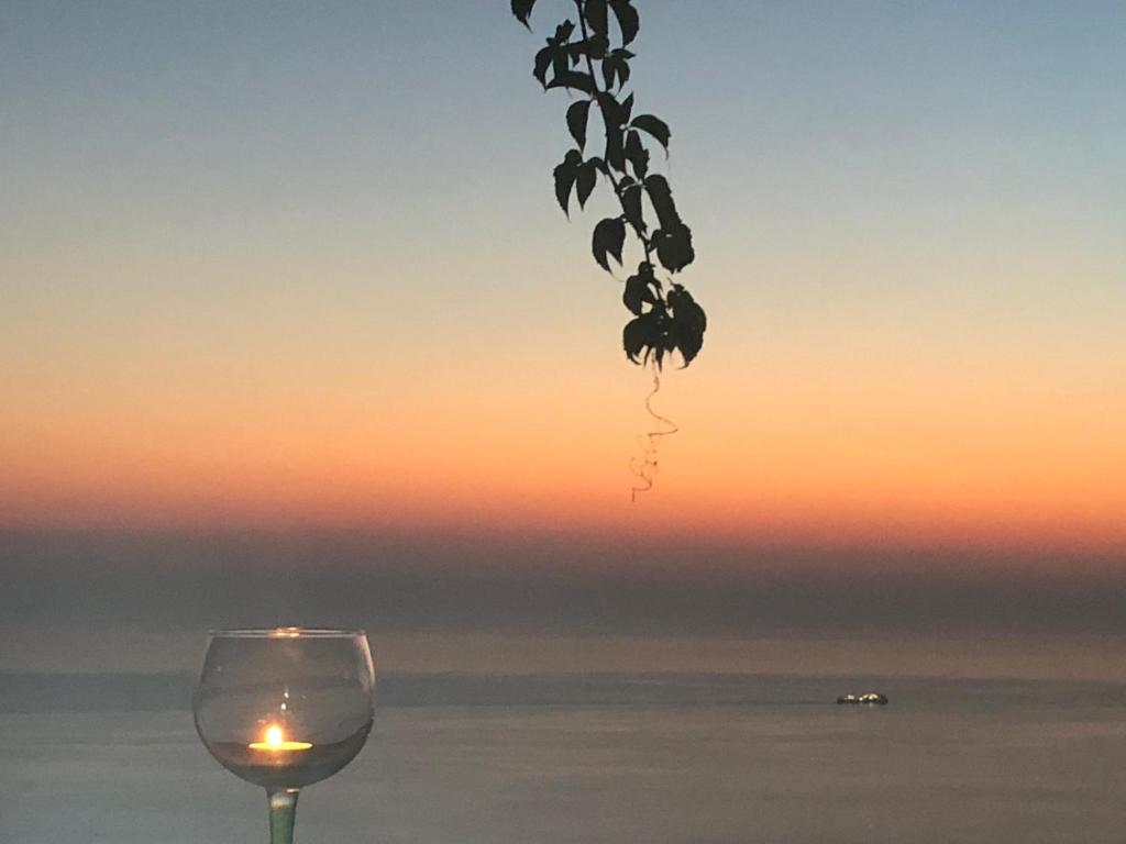 a wine glass sitting on a table with a sunset in the background at Tajo VIllas in Athani