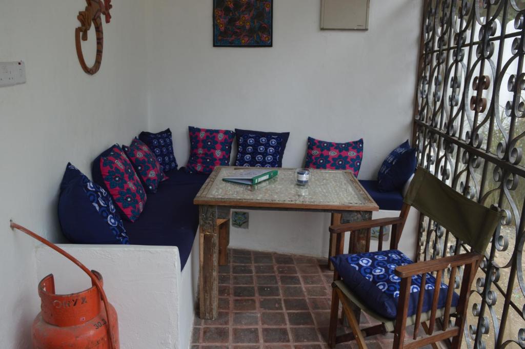 Zimmer mit einem Tisch und einem Sofa mit Kissen in der Unterkunft Gecko Cottage in Bagamoyo