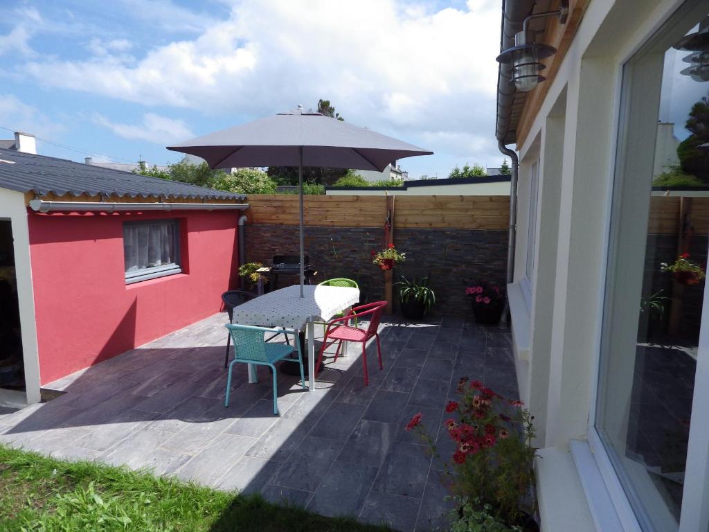 Un patio con una mesa y sillas y una sombrilla. en TY KASTELL PAOL, en Saint-Pol-de-Léon