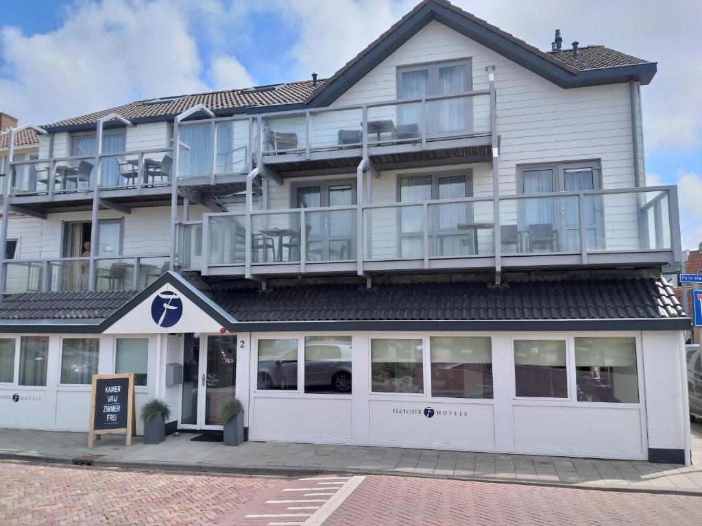 a large white building with a lot of windows at Fletcher Badhotel Egmond aan Zee in Egmond aan Zee