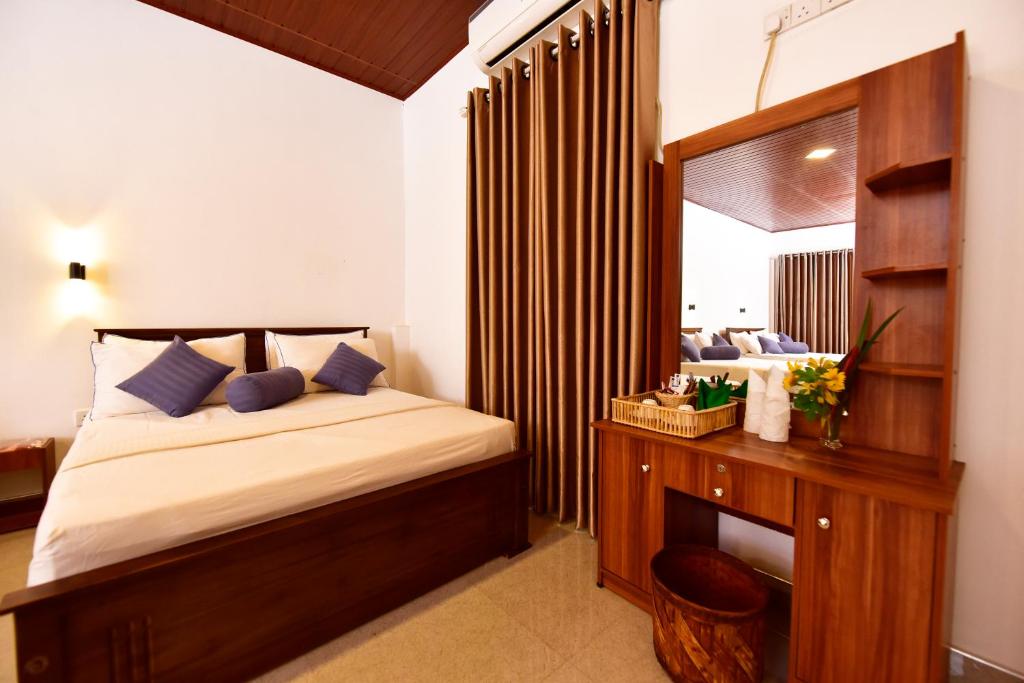 a bedroom with a bed and a desk with a mirror at Ariya Rest & Ayurveda spa in Polonnaruwa