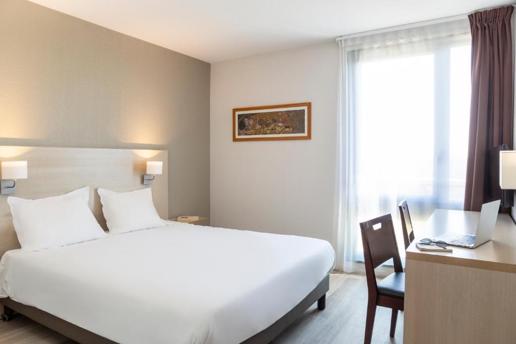 Habitación de hotel con cama blanca grande y escritorio. en Aparthotel Adagio Access Avignon, en Aviñón