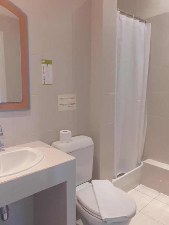 a white bathroom with a toilet and a sink at Hôtel P.L.M. in Cannes