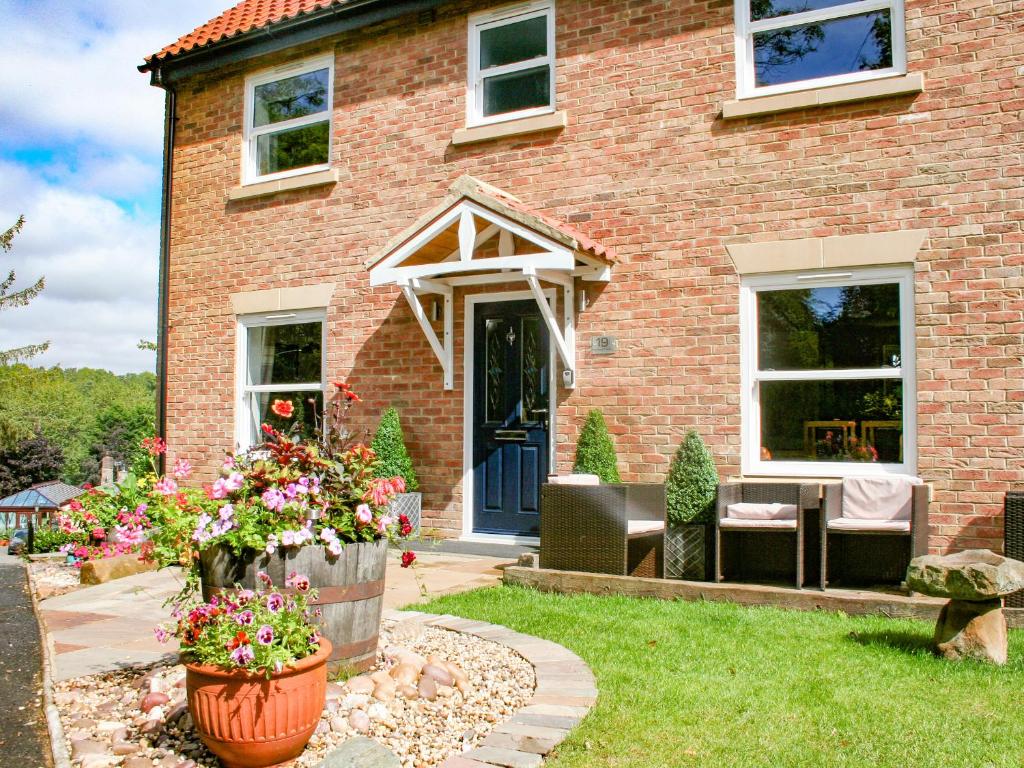 una casa di mattoni con una porta blu e alcuni fiori di Sycamore Cottage a Yarm