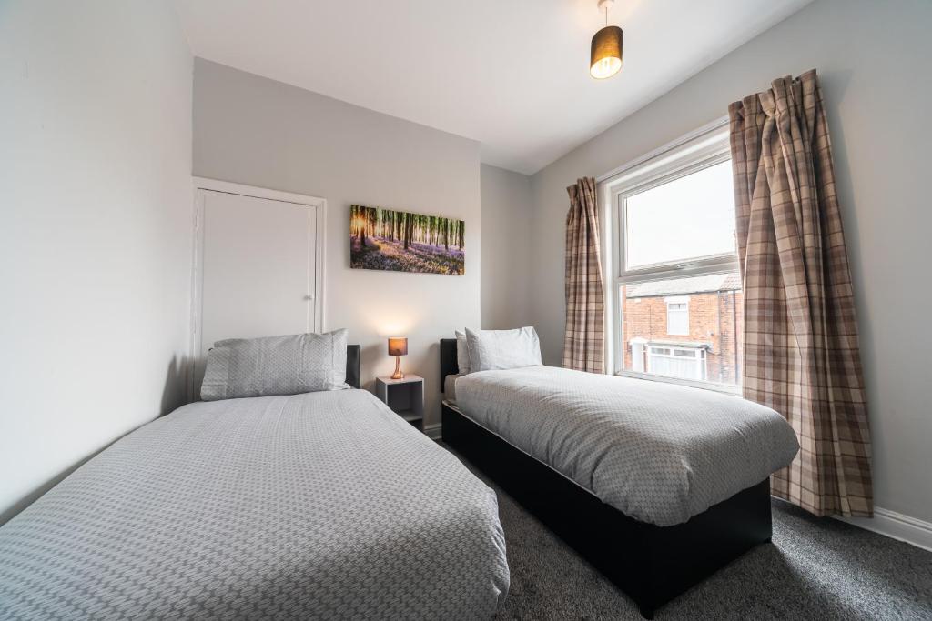 two beds in a bedroom with a window at 3 Bedroom Hull Sleeps 6 Glam Contractor & Leisure & Families Close to Clough Rd in Hull
