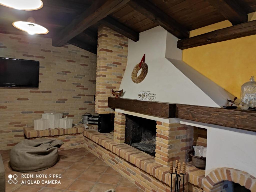 sala de estar con chimenea de ladrillo y TV en La taverna di lulu, en Arnesano