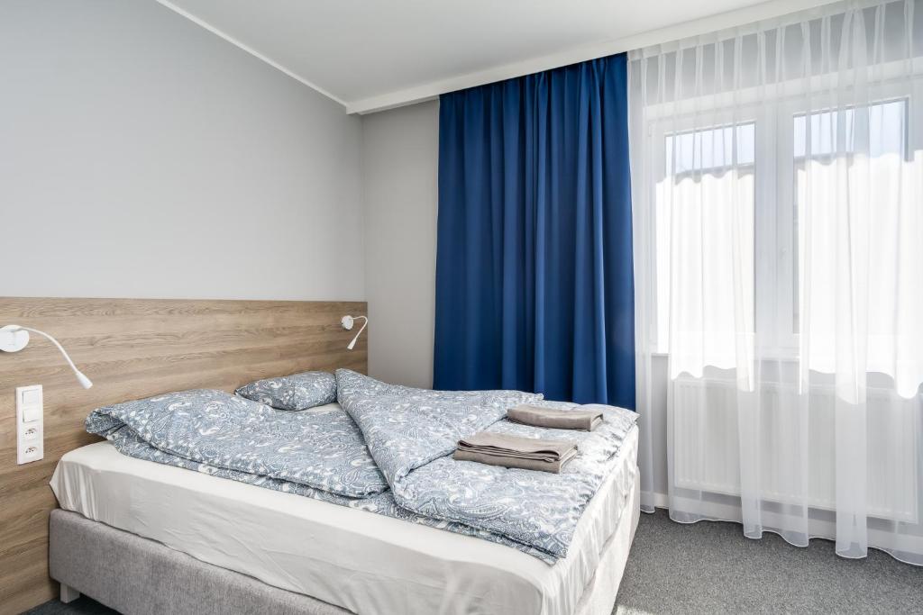 1 dormitorio con 1 cama con cortinas azules en Hugo, en Gdynia
