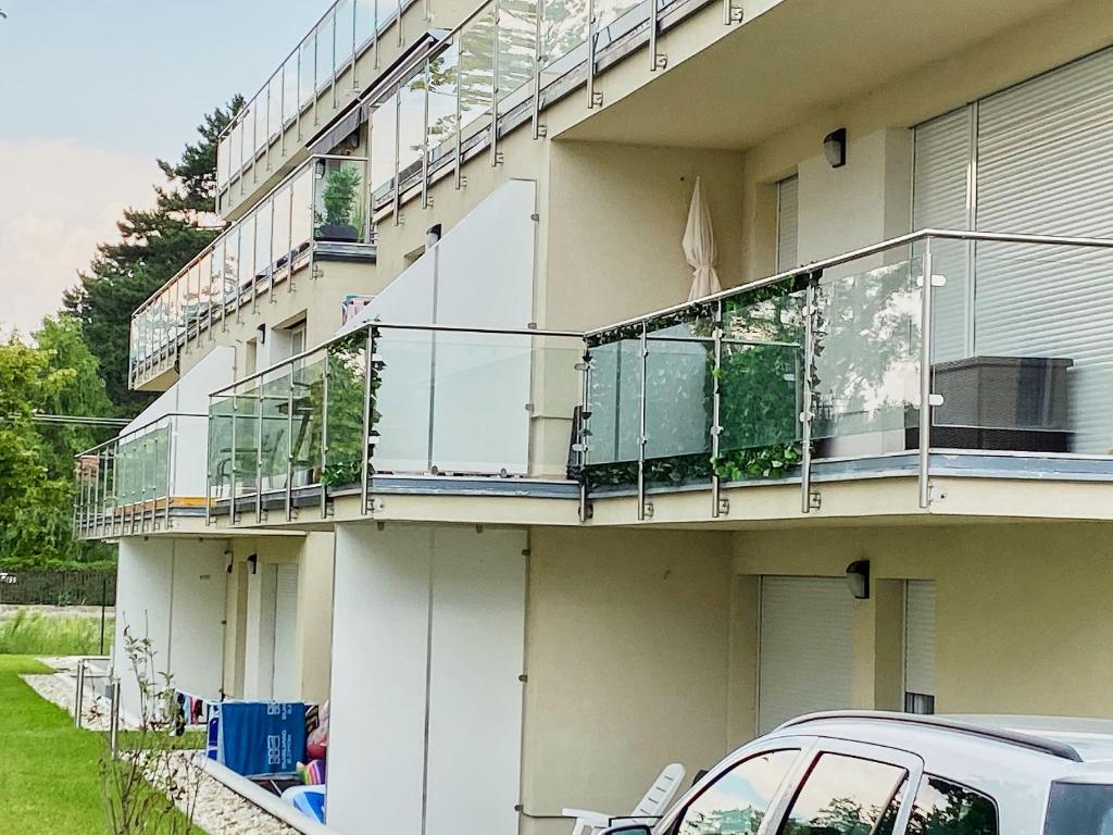 een gebouw met balkons en een auto voor het gebouw geparkeerd bij SunGarden Apartments - hostAID in Siófok