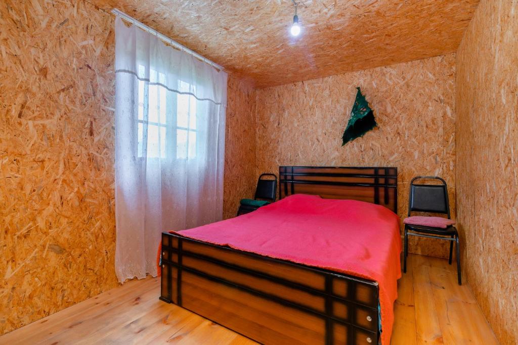 a bedroom with a red bed and a window at Guesthouse Elisabeth in Omalo