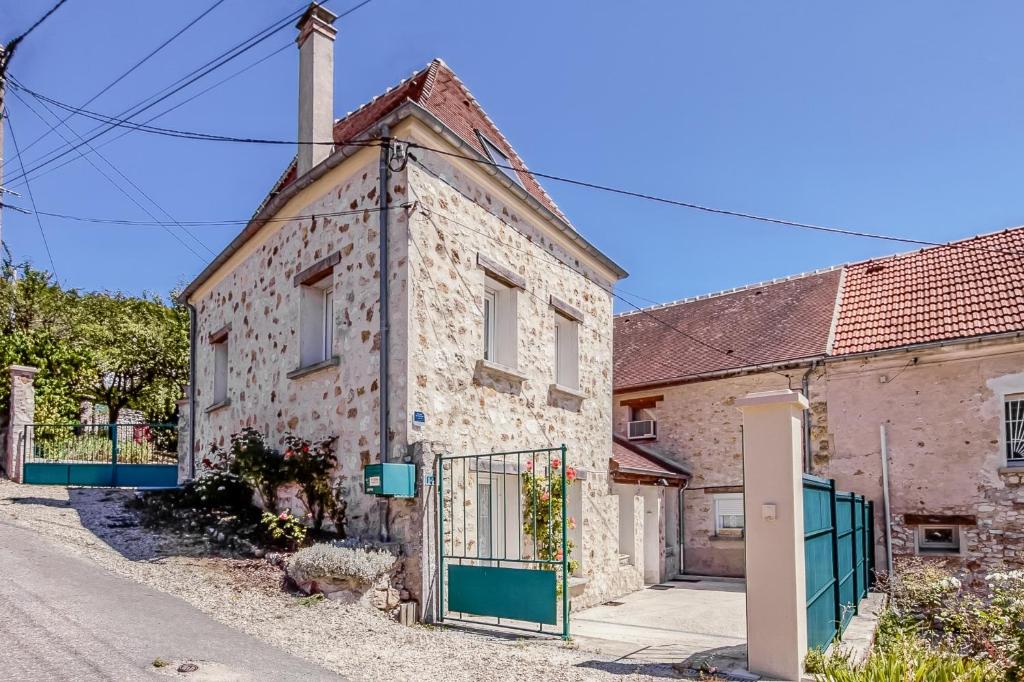 an old stone house with a green gate on a street at Gîte Leomie - Maison en pierre au pied des vignes - Monthurel in Monthurel