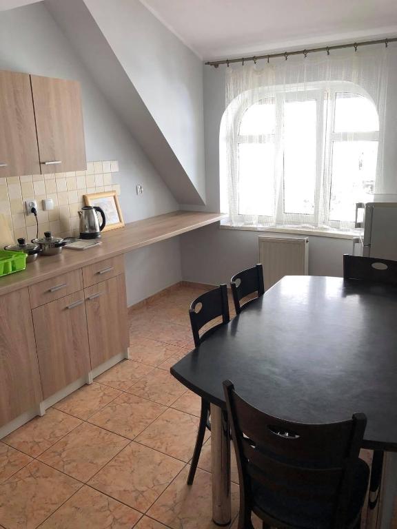 a kitchen with a black table and chairs and a table and a window at Apartamenty nad jeziorem - 4 in Ełk