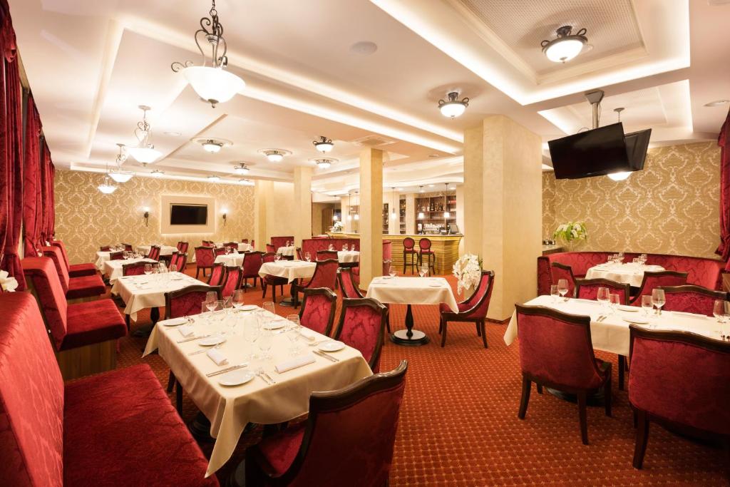 a restaurant with tables and chairs and a television in a room at Hotel Dvorana in Karlovy Vary