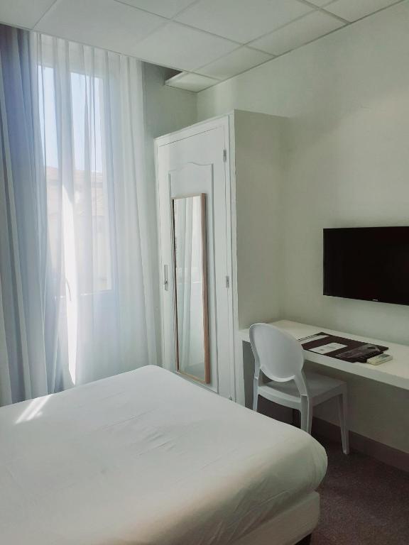 a bedroom with a bed and a desk with a computer at Hôtel P.L.M. in Cannes