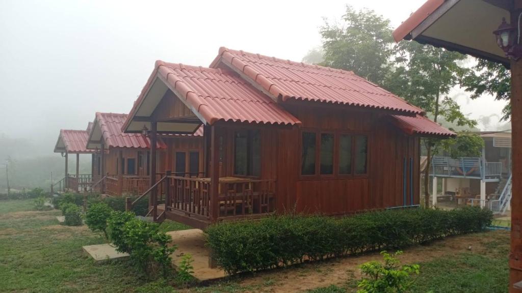 Cabaña de madera con techo rojo en บ้านในสายหมอกบุญแจ้งโฮมสเตย์ en Khao Kho