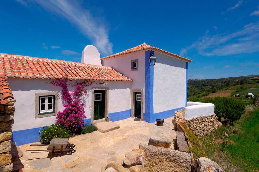 a small white house with purple flowers in front of it at Aldeia da Mata Pequena in Mafra