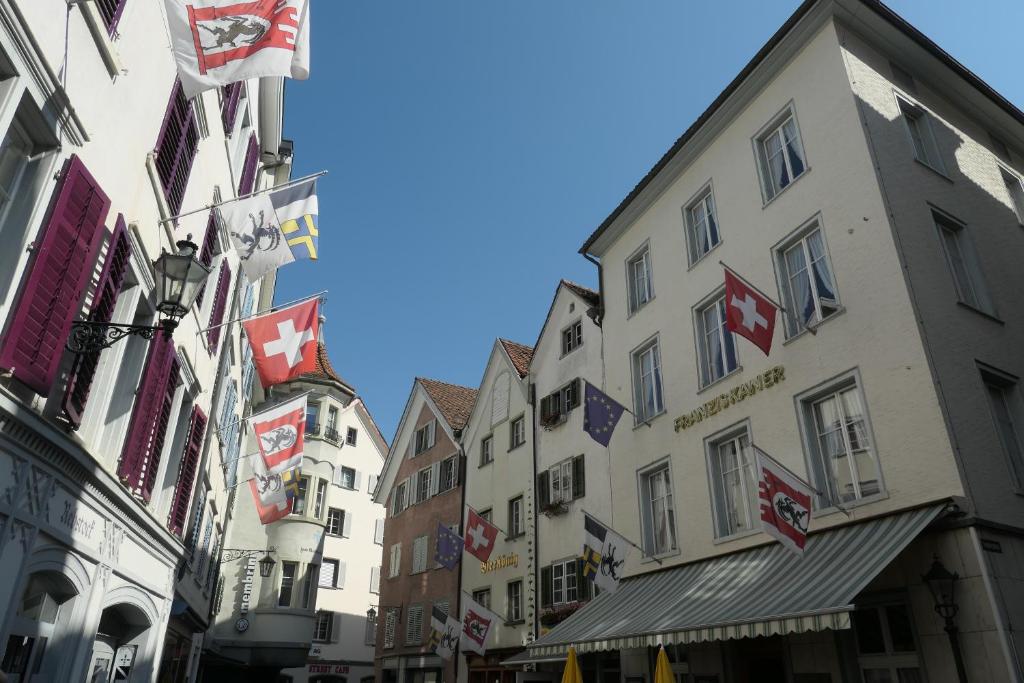 une rue de la ville avec des bâtiments et des drapeaux dans l'établissement Hotel Franziskaner, à Coire