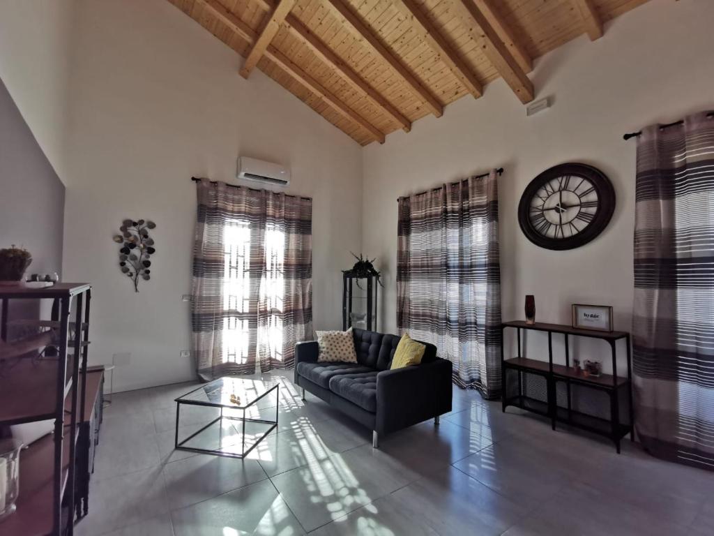 Hygge House Catania في كاتانيا: غرفة معيشة مع أريكة وساعة على الحائط