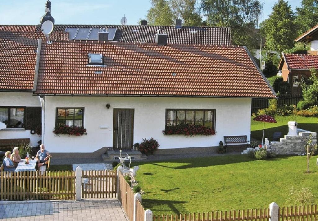 a white house with people sitting at a table in a yard at Ferienhaus Baumann in Neukirchen beim Heiligen Blut