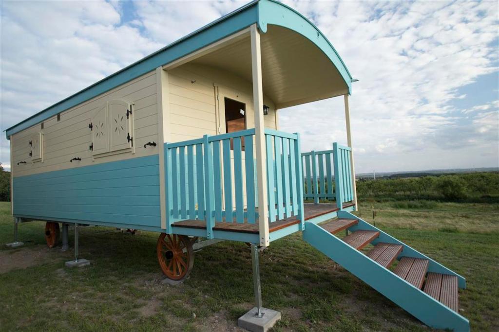 a blue and white play house on wheels in a field at Zauberwagen Zirkuswagen Naturwagen in Kröpelin