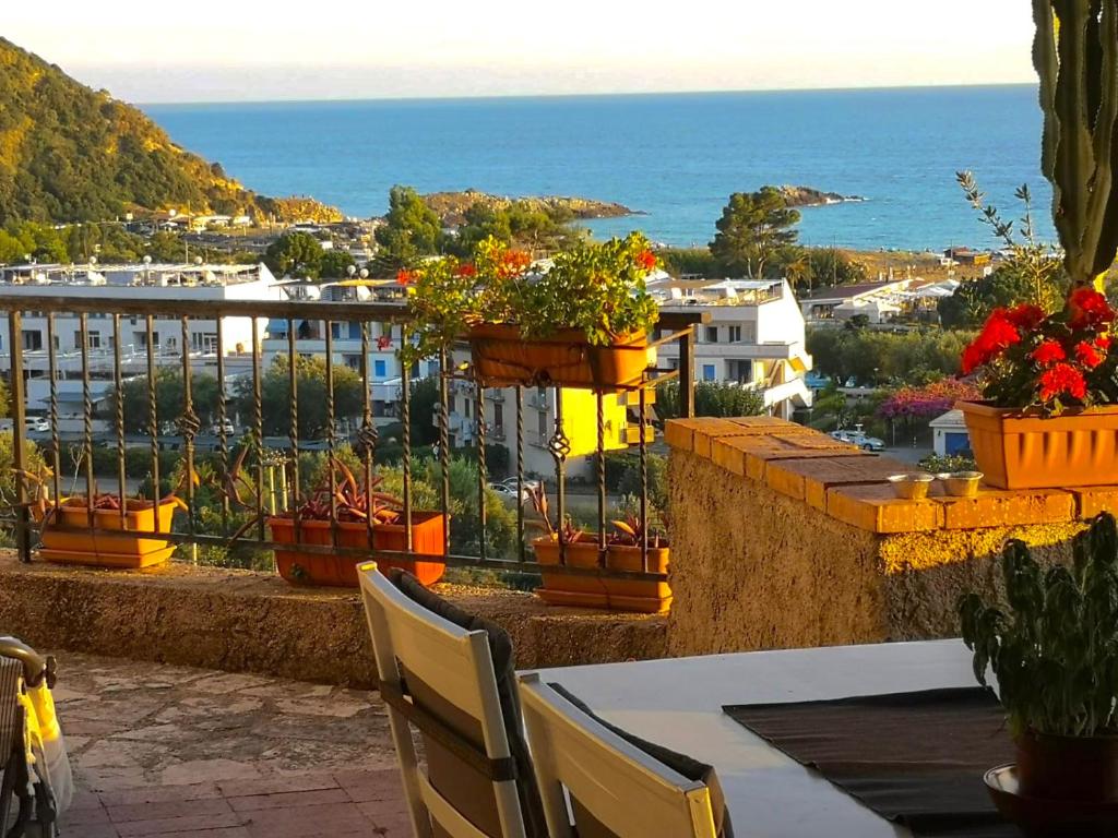 uma varanda com mesa, cadeiras e flores em Villa Lo Scoglio em Ascea