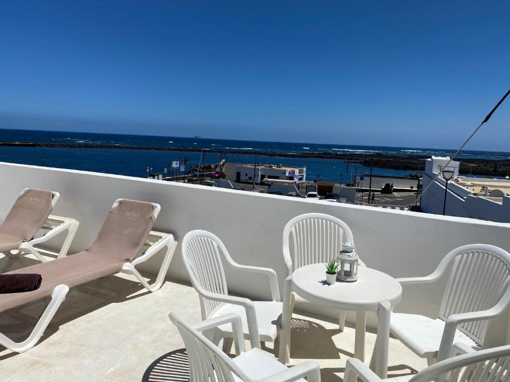 a balcony with chairs and a table and a view of the ocean at Mirador del muelle house in Orzola