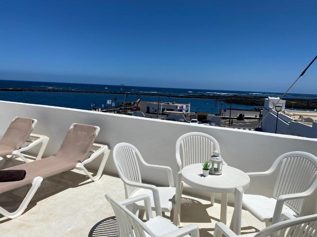 a balcony with chairs and a table and a view of the ocean at Mirador del muelle house in Órzola