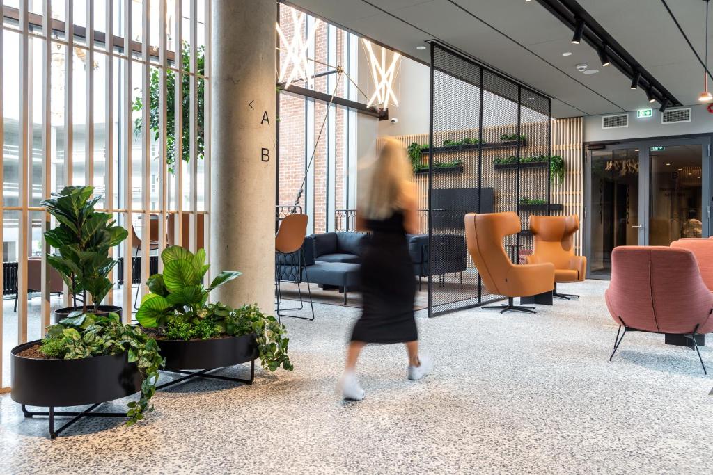 a woman walking through a lobby with plants and chairs at Citybox Tallinn City Center in Tallinn