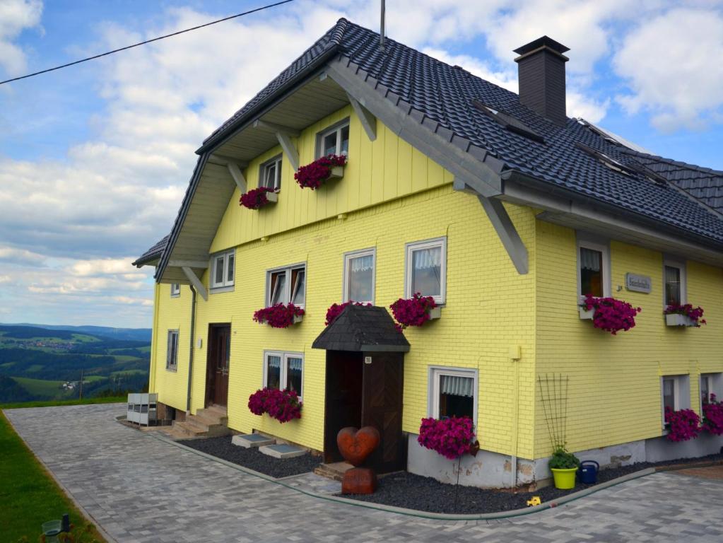 ein gelbes Haus mit Blumen auf der Seite in der Unterkunft Bäuerleshütte in Breitnau