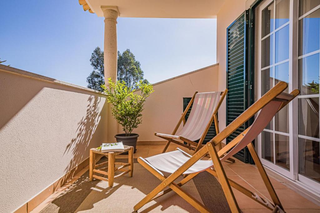 a pair of chairs on the balcony of a house at Buganvilias Do Meco Guest house in Sesimbra