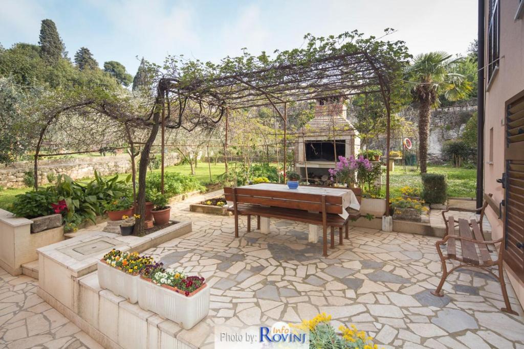 um jardim com uma mesa e uma pérgola em Ondina em Rovinj