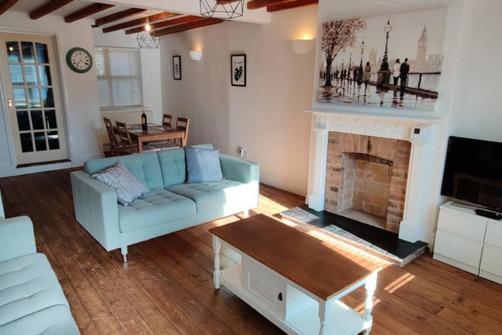 a living room with a blue couch and a fireplace at Bank House in Lutterworth