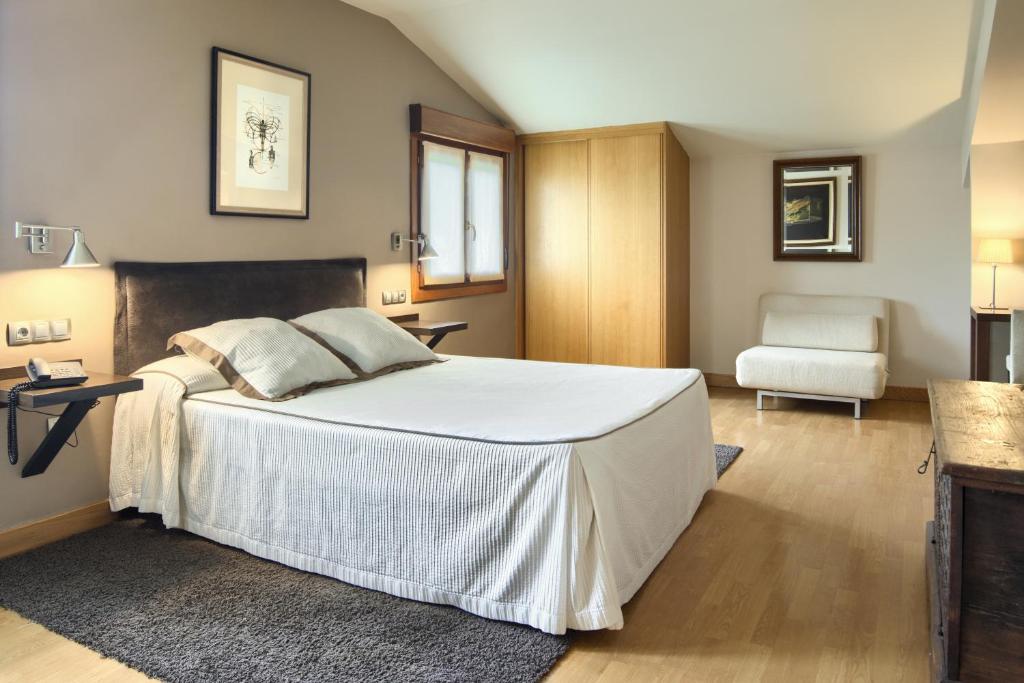 een slaapkamer met een groot wit bed en een stoel bij Hotel Rural Izar Ondo in Arbizu