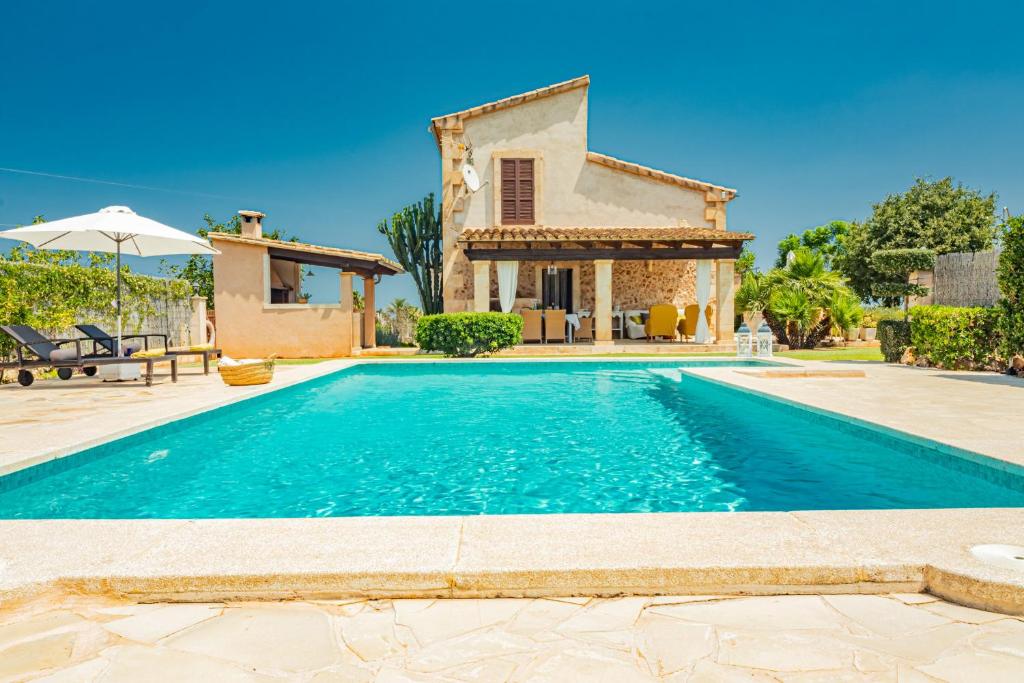 a villa with a swimming pool in front of a house at Finca CARRITX in Can Picafort