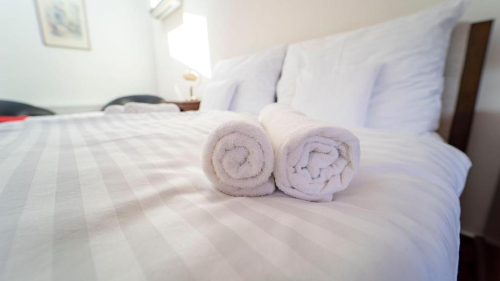 2 toallas sentadas encima de una cama blanca en Penzión Rosel en Nové Zámky