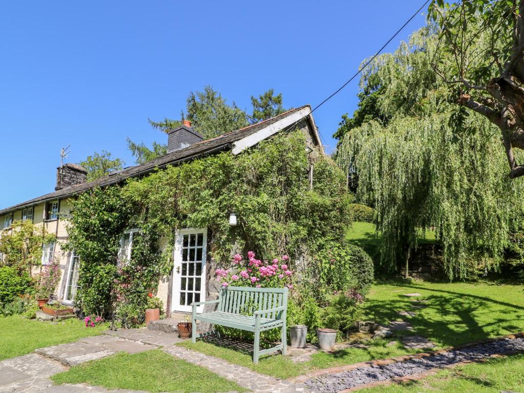 ein Haus mit einer Bank davor in der Unterkunft Lower Dolgenau The Cottage in Caersws